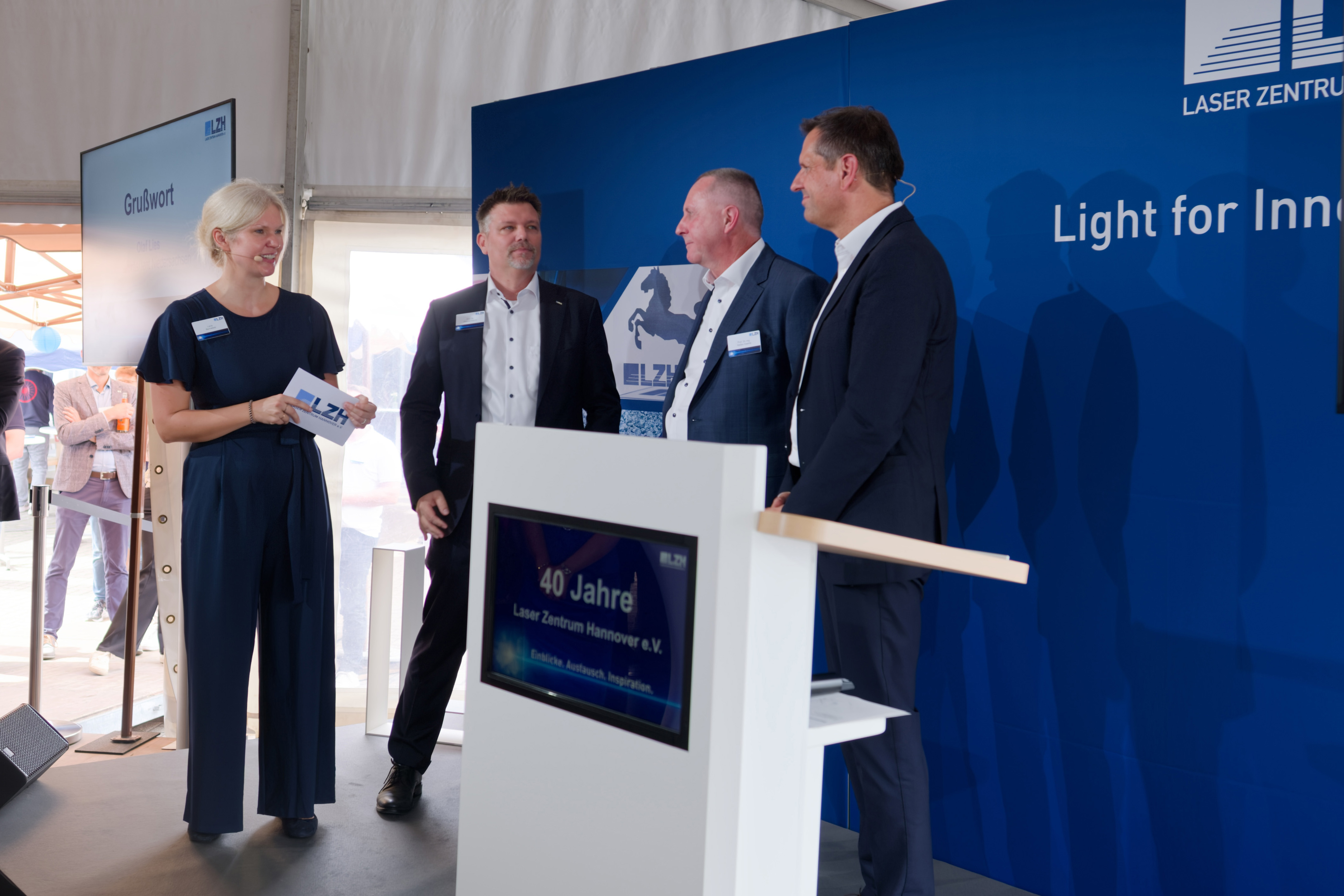 Die Geschäftsführung des LZH, drei Personen, stehen zusammen mit dem Ministerpräsidenten.
