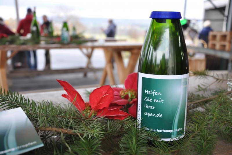Geschnittene Weinflasche als Spendenbox im Einsatz auf dem Weihnachtsmarkt