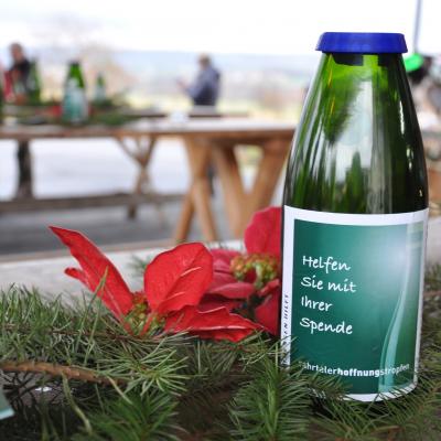 Geschnittene Weinflasche als Spendenbox im Einsatz auf dem Weihnachtsmarkt