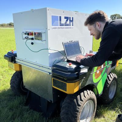 Wissenschaftler arbeitet am Laptop mit Feldroboter.