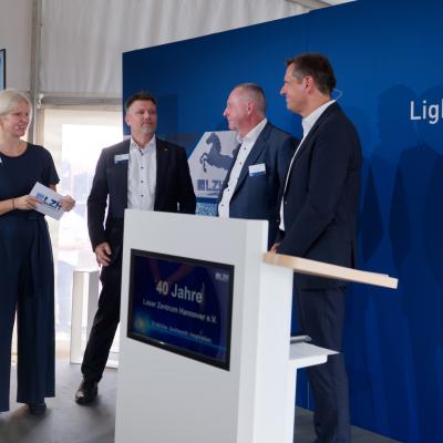 Die Geschäftsführung des LZH, drei Personen, stehen zusammen mit dem Ministerpräsidenten.