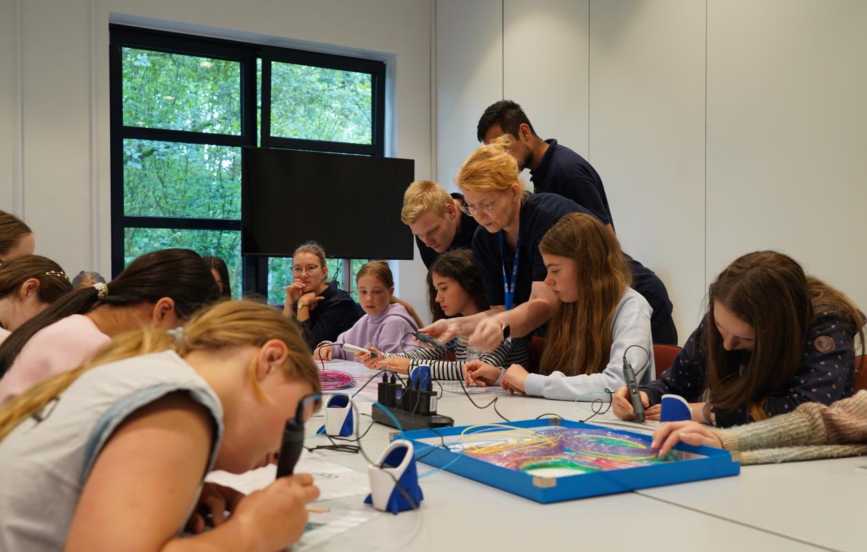 Mehrere Kinder sitzen an einem Tisch und nutzen 3D-Druckstifte.