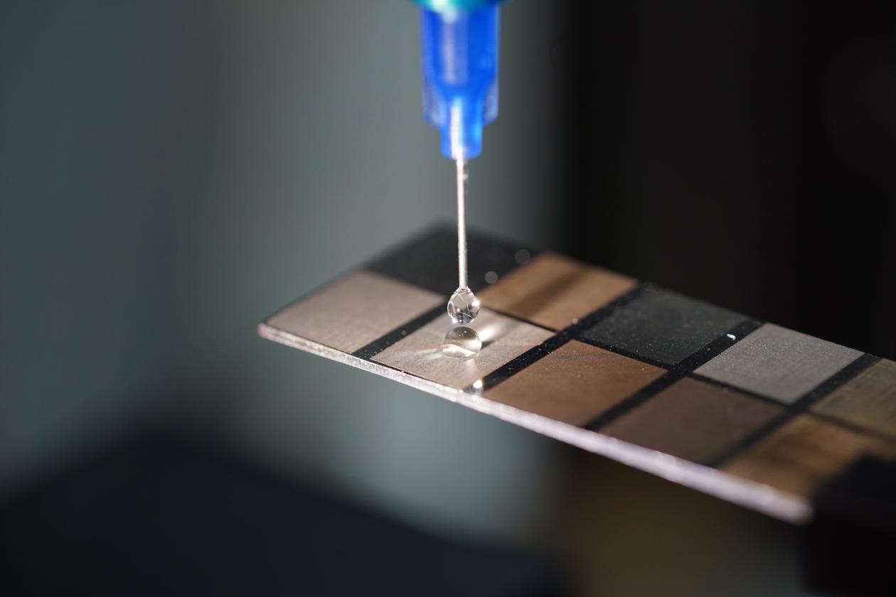 Pipette tropft Flüssigkeit auf wasserabweisende Oberfläche.